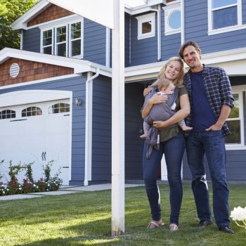 Family posing in front of newly purchased home